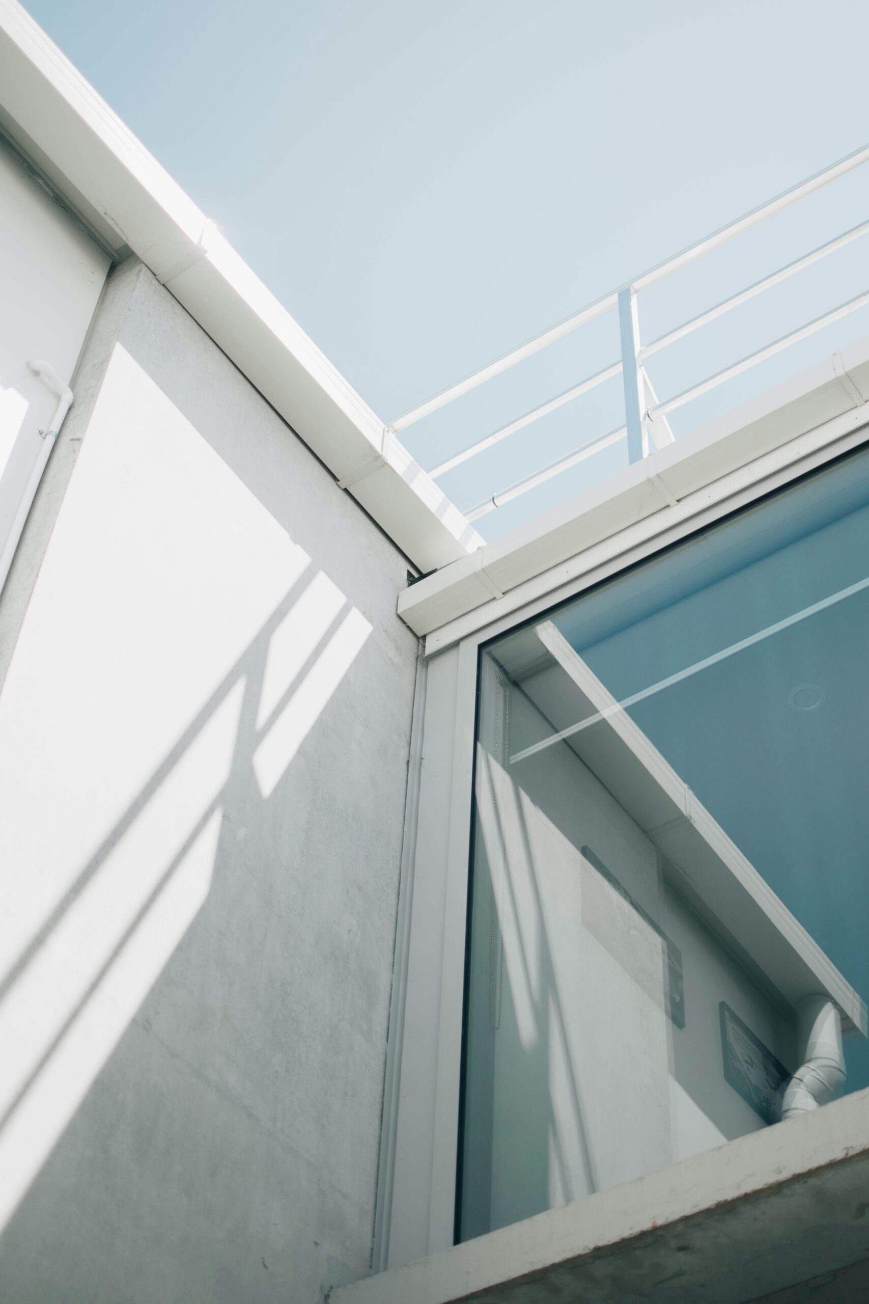 A minimalist architectural design featuring glass and steel elements on a sunny day.